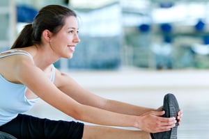 Woman doing stretching exercises for her leg at the gym