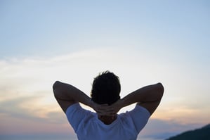 handsome young man relaxing and working on laptop computer at home balcony while looking sunset-1